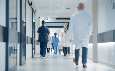Hospital hallway photo of nurses and doctors walking away down hall photo